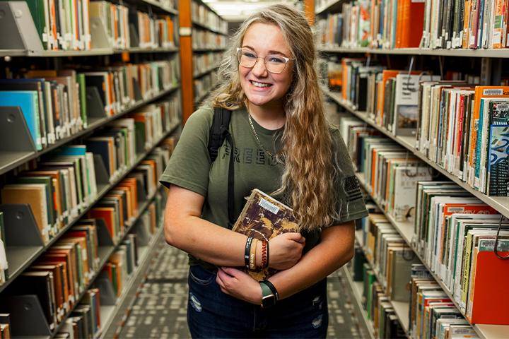 A WSC student poses in the library between book stacks