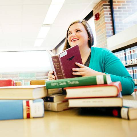 A WSC student surrounded by several books