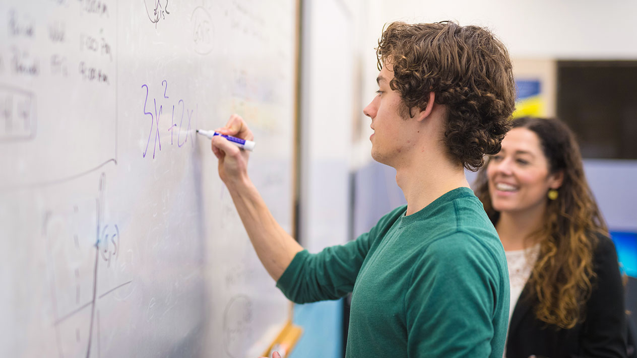 A math teacher and student solve equations in class