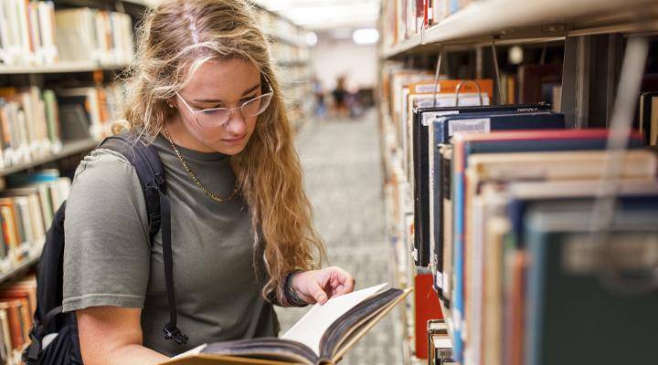 A student in the library surrounded by books