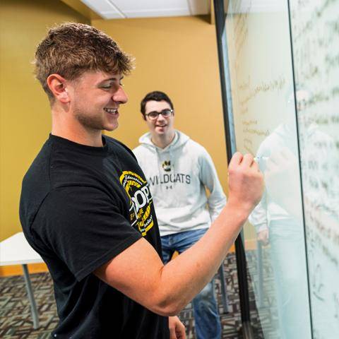 A student and tutor work out math problems on a whiteboard
