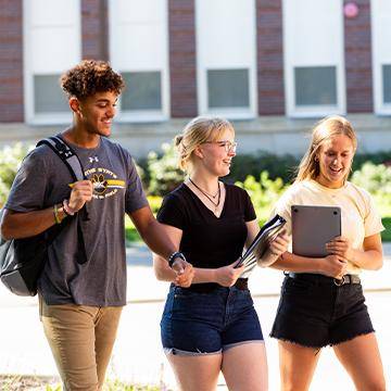 Three students walk on campus