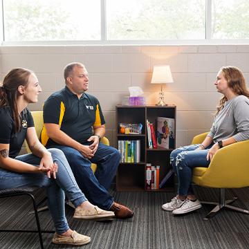 Two faculty and a student talk in a counseling room