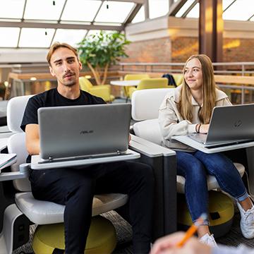 Two students work on laptop computers