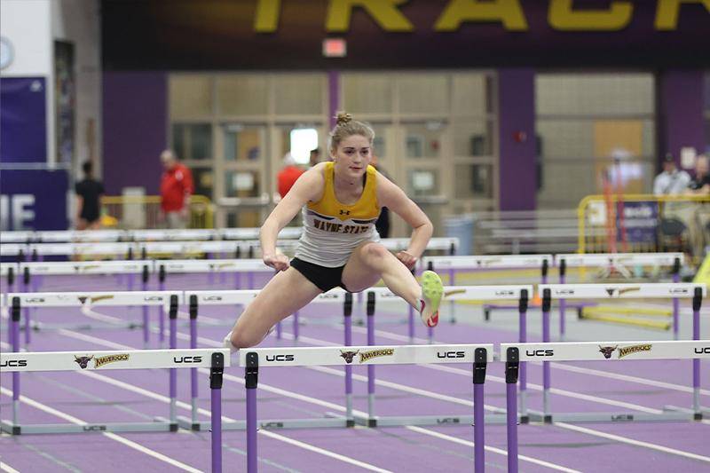 A female jumps over a hurdle