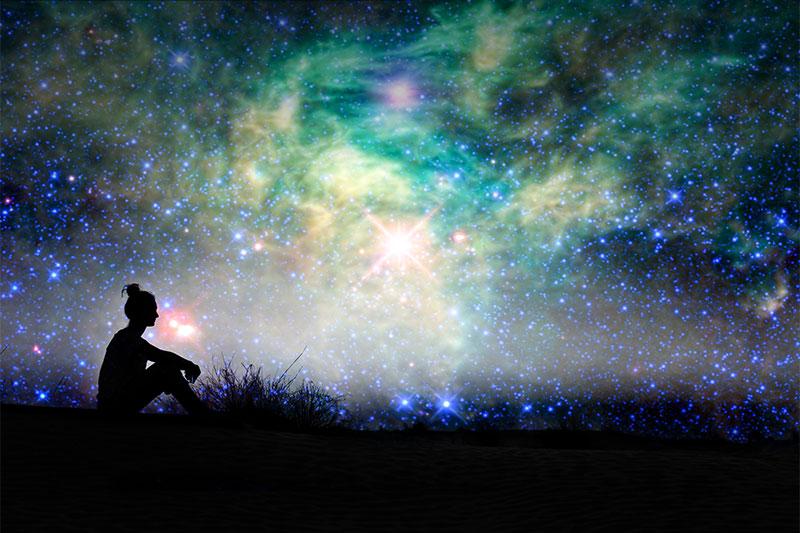 Silhouette image of a woman looking at the colorful night sky
