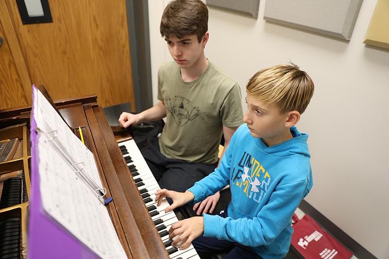 A Music Academy student works with a WSC student teacher on piano