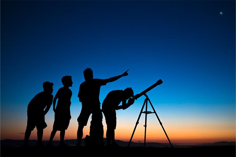 Silhouette photo of children looking at the night sky through a telescope
