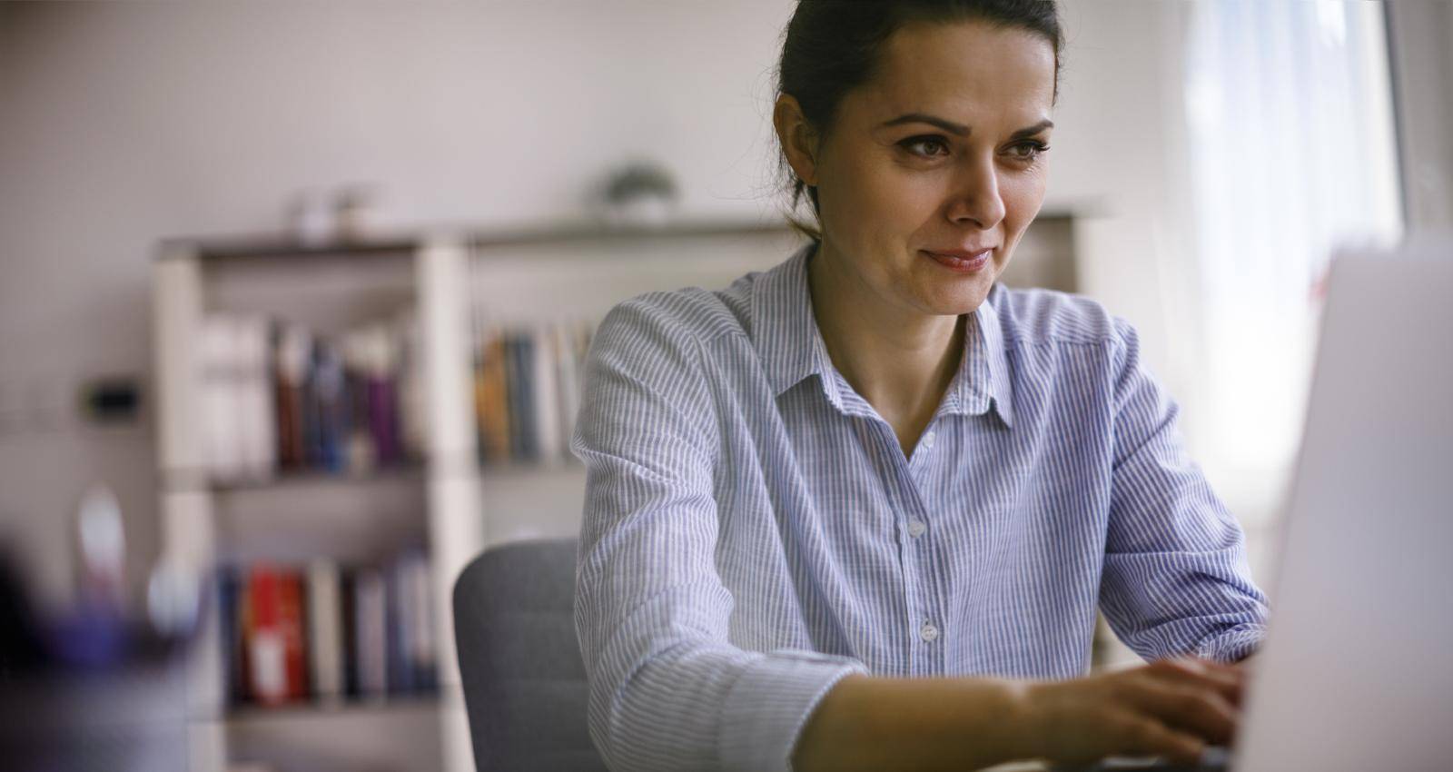 A woman works on a laptop in her home