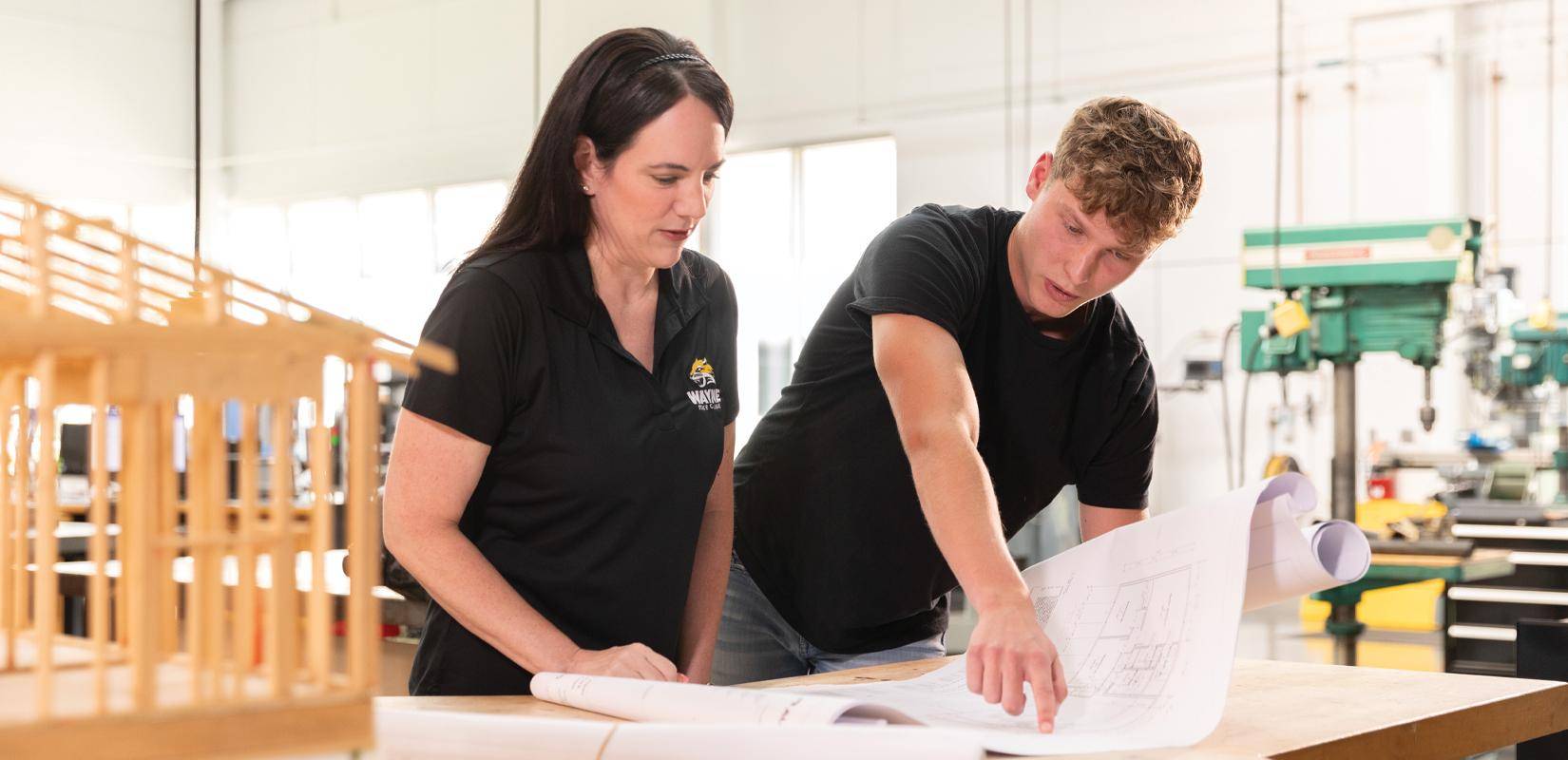 An industrial tech student reviews a blueprint with his professor