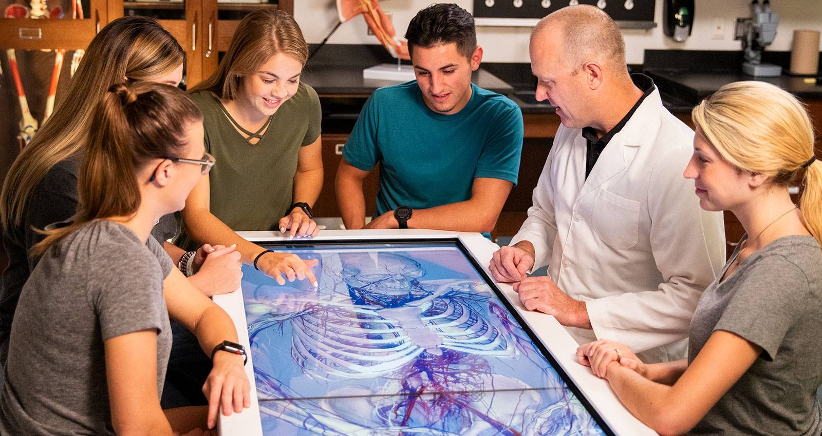 A professor and students use the Anatomage Table in the biology lab