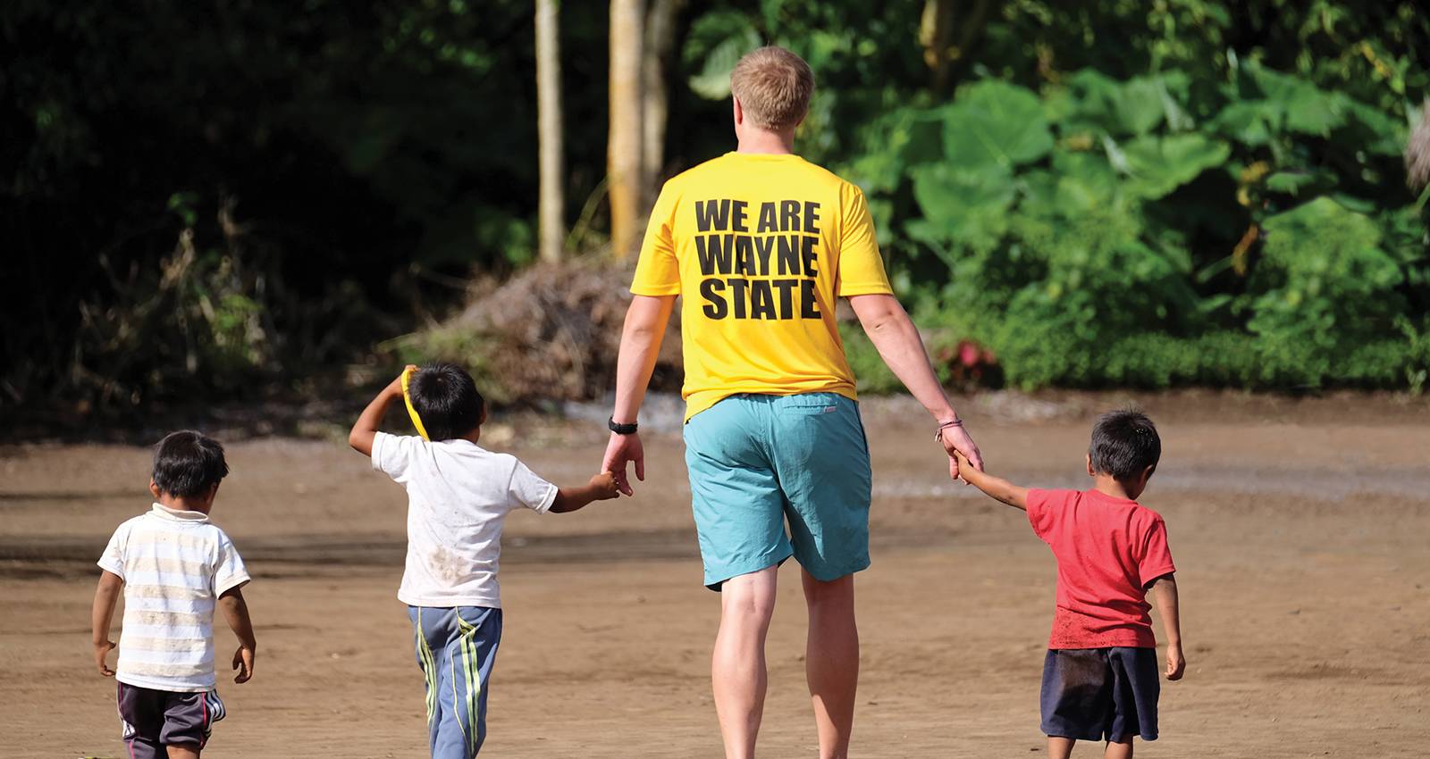 A Wayne State student guides young children on a mission trip