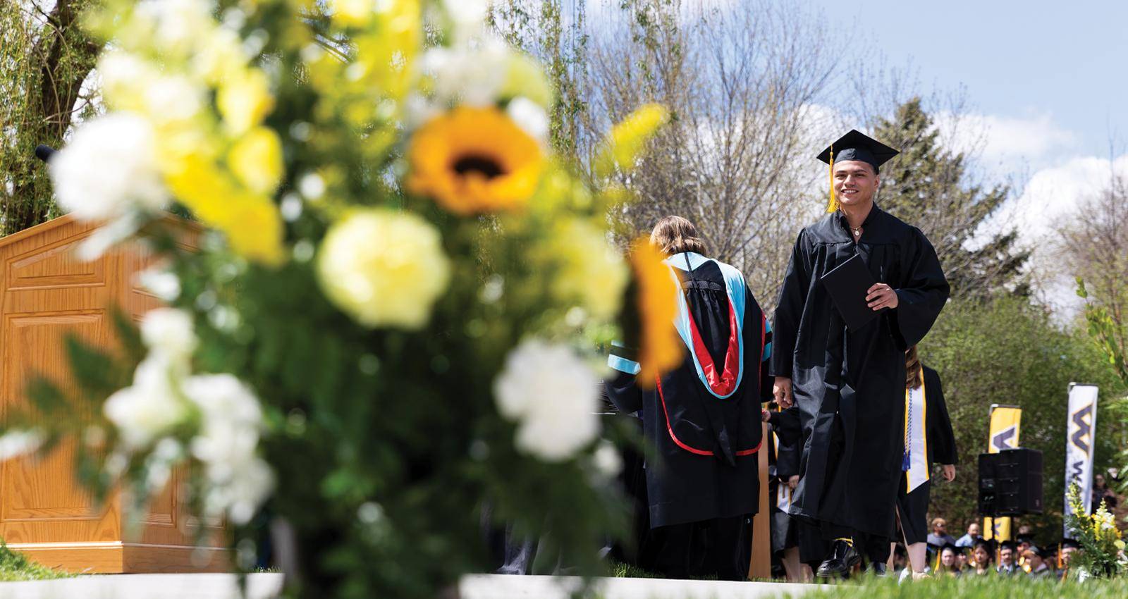 A student walks across the state at a spring commencement ceremony