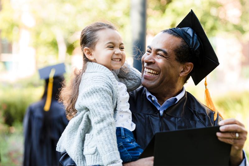 An older man holding his daughter graduates from college