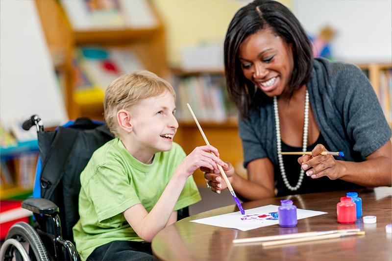 A special education teacher helps a boy with special needs.