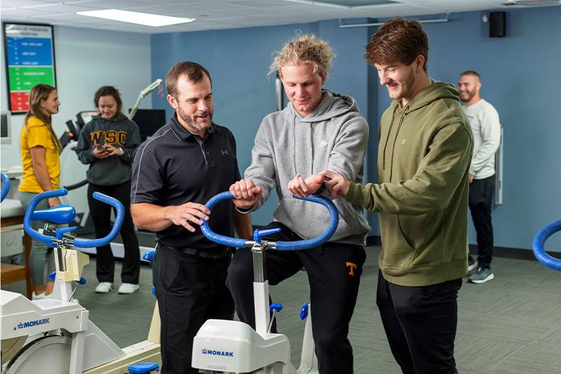 Exercise science degree students work with a professor in the human performance lab at WSC