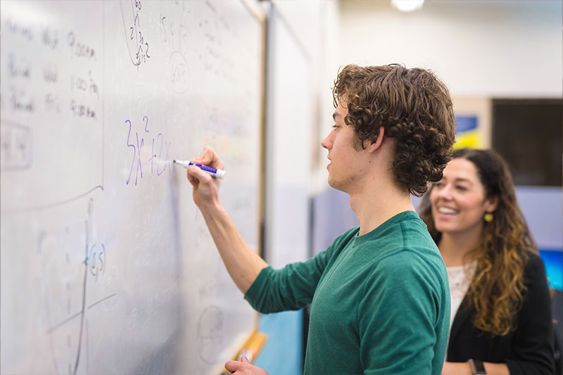 Math education degree concept featuring a student and teacher working on a math equation