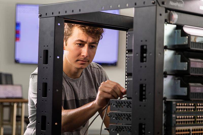 A networking and cybersecurity degree student works in the networking lab at WSC