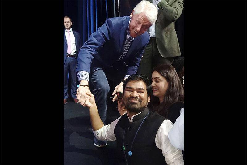 Photo of student Roshan Yadav shaking hands with former President Bill Clinton