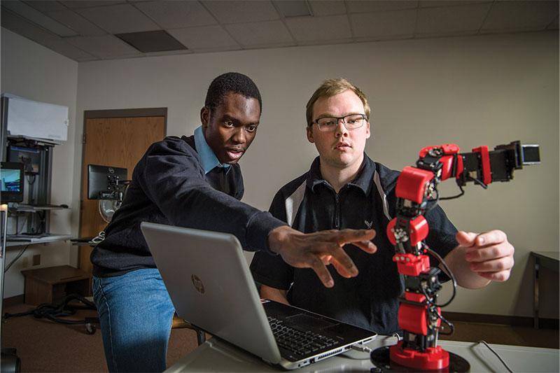 Oswald Adohinzin (left) works with another student on a robot.