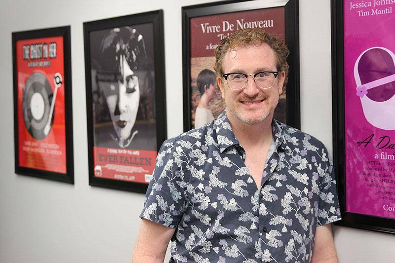 Photo of Dr. Mike White next to film posters