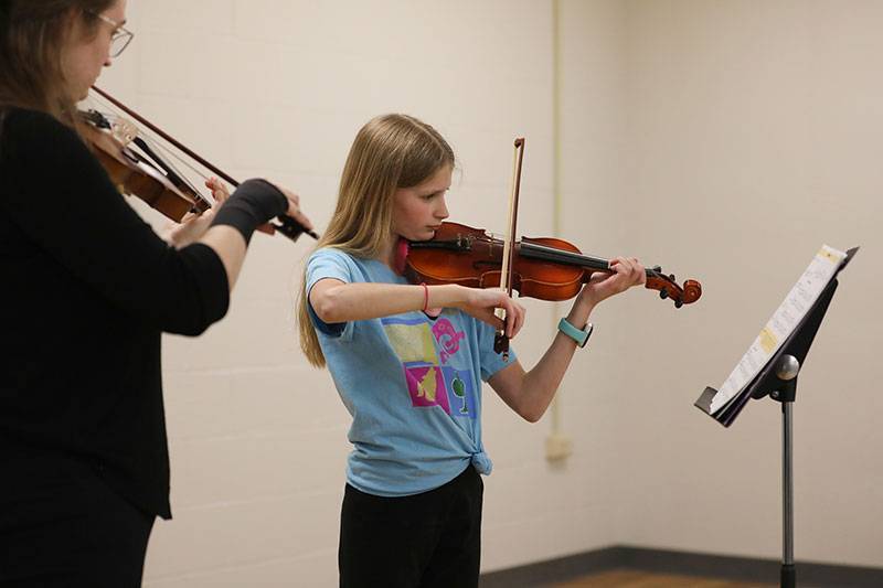 A student receives a violin lesson during Music Academy