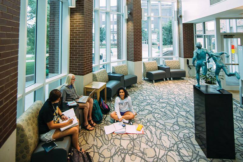 Three students study in the atrium of the library