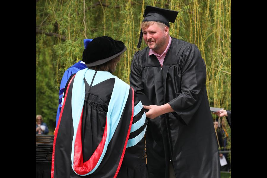 A photo of Bennett Lamplot receiving his diploma during commencement.
